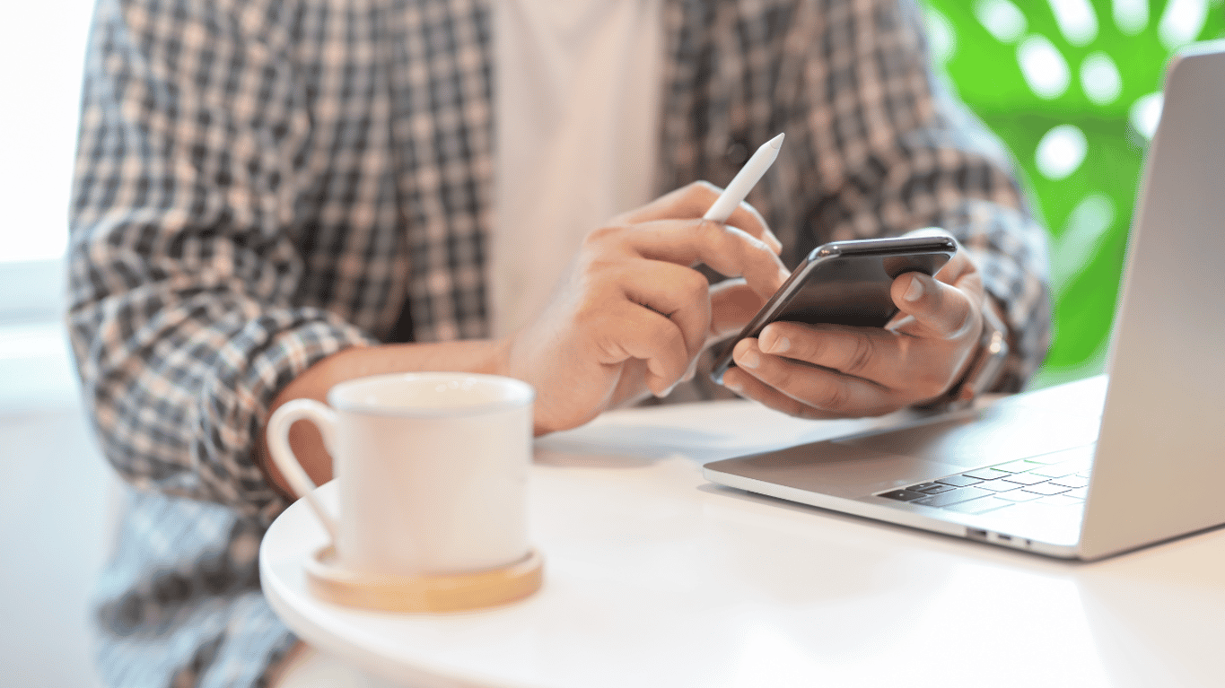 Person sitting with laptop cell phone and cup of coffee getting ready to contact us